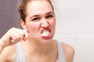 aggressive healthy dental care for beautiful young woman in bathroom