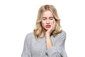 Young Woman Suffering From Toothache. Tooth Pain And Dentistry background. Beautiful Young Woman Suffering From Terrible Teeth Pain, Touching Cheek With Hand.