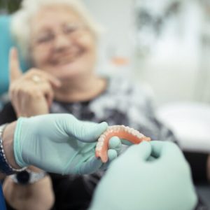Dentist showing teeth dentures to a patient