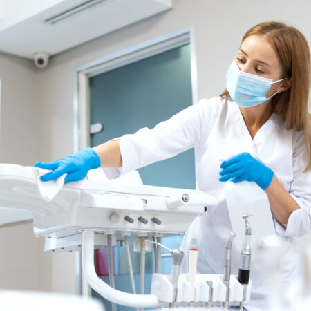 Side view of dentist assistant wiping modern dental equipment. Contemporary stomatology clinic service. Oral medicine sector. Safety and sanitary standards compliance